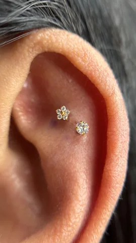 Dos piercings en la oreja con joyas florales