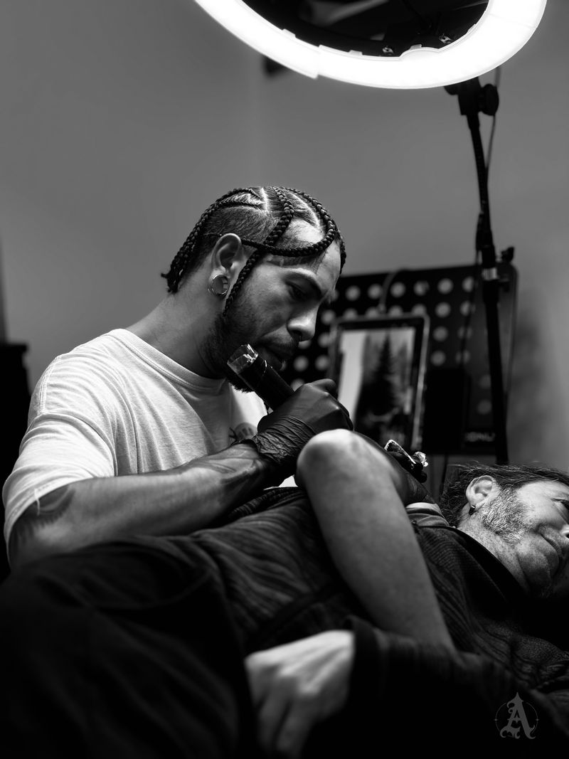 Frank, resident tattoo artist at Arkadia, tattooing in a booth