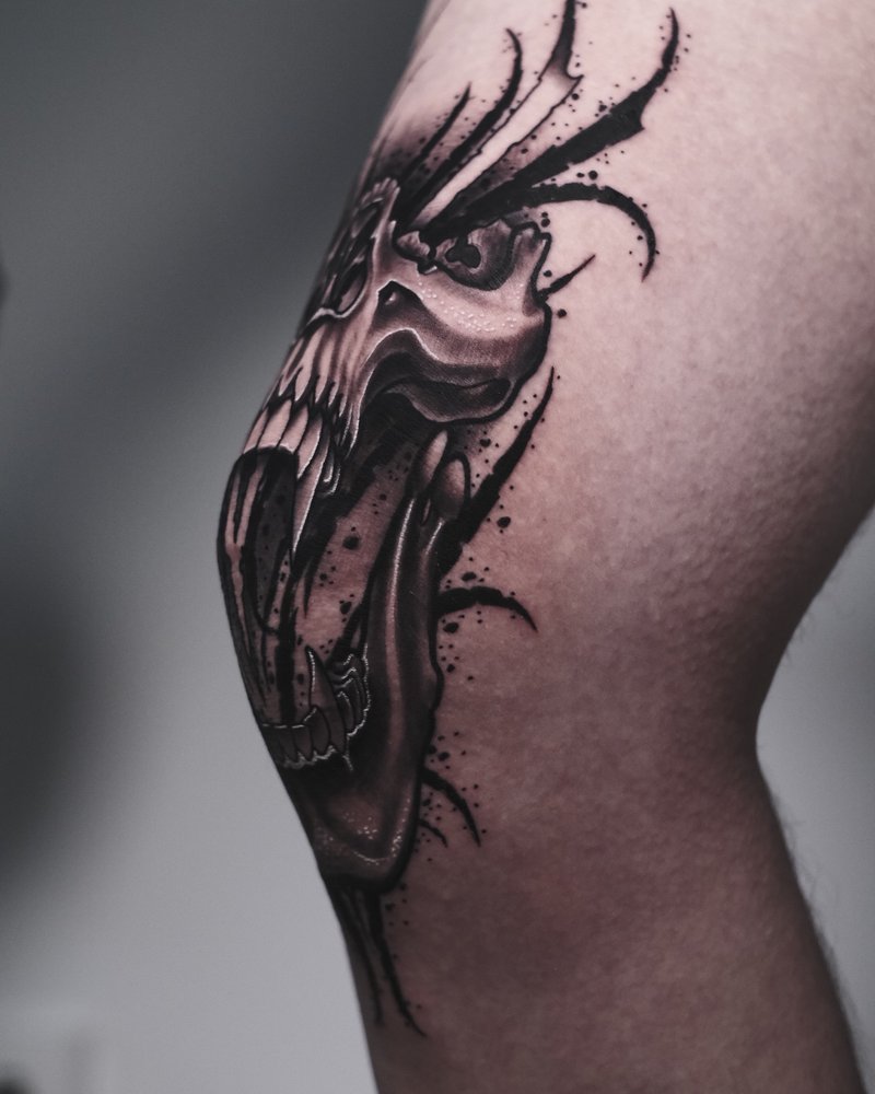 Tatuaje blackwork de una criatura alada en la rodilla