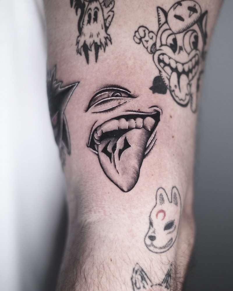 Tatuaje con varios dibujos sueltos: calaveras, bocas y un conejo, en el antebrazo
