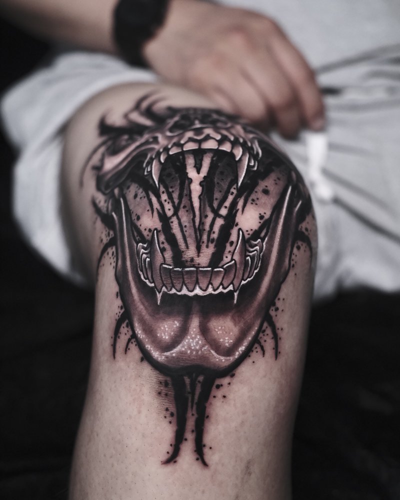 Tatuaje blackwork de unas fauces abiertas con tinta chorreando, en el antebrazo