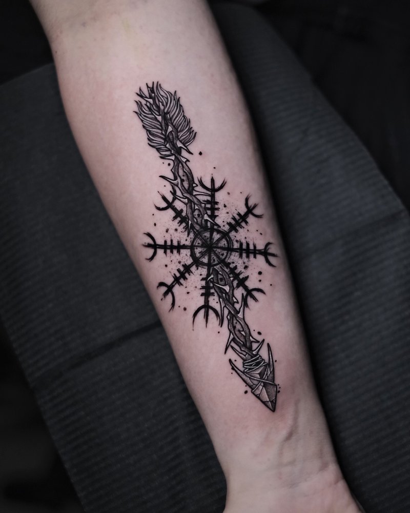 Tatuaje de una daga sobre un mandala radial en puntillismo, en el antebrazo