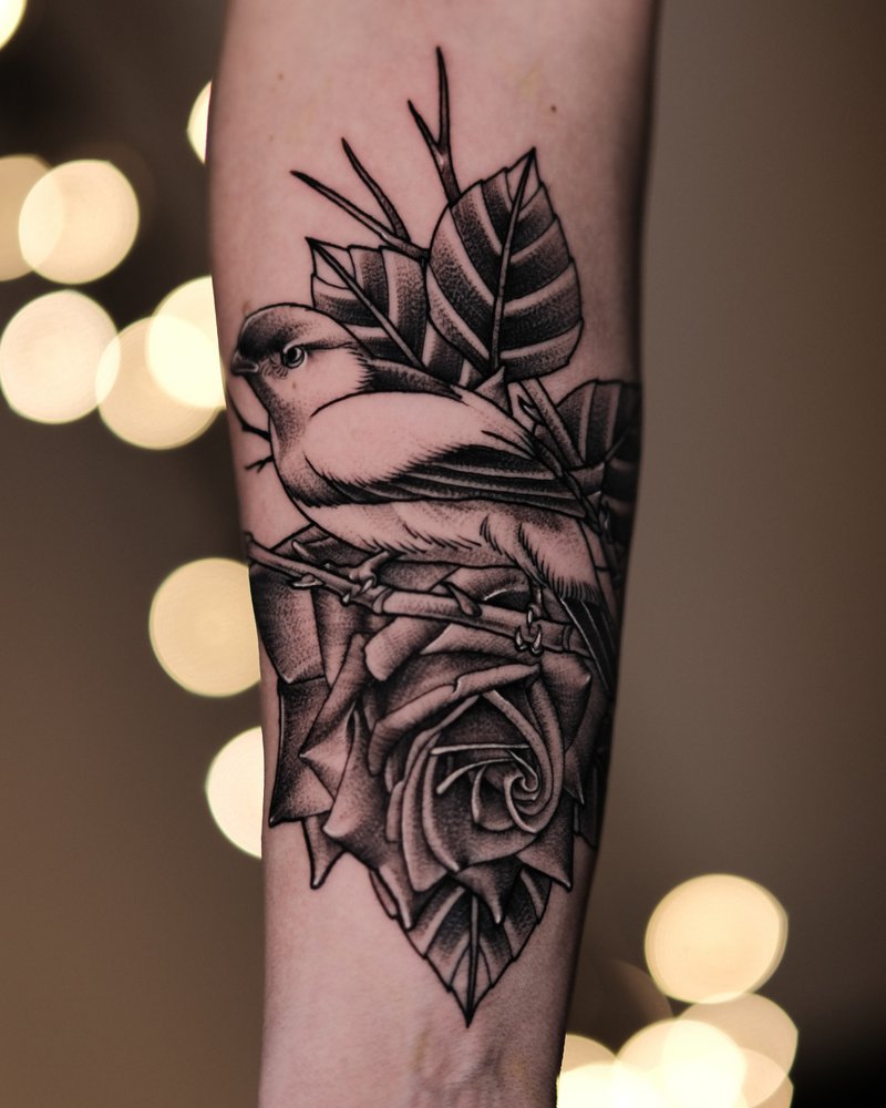 Tatuaje de línea fina con una mariposa y una flor, en el antebrazo