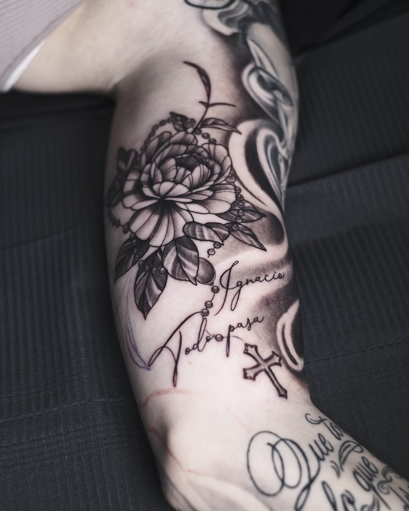 Tatuaje de línea fina con rosas y lettering manuscrito, en el antebrazo