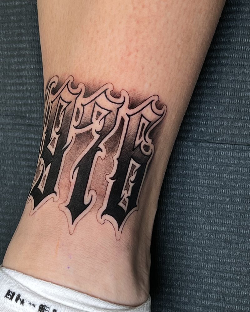 Tatuaje de lettering gótico en negro en la pantorrilla