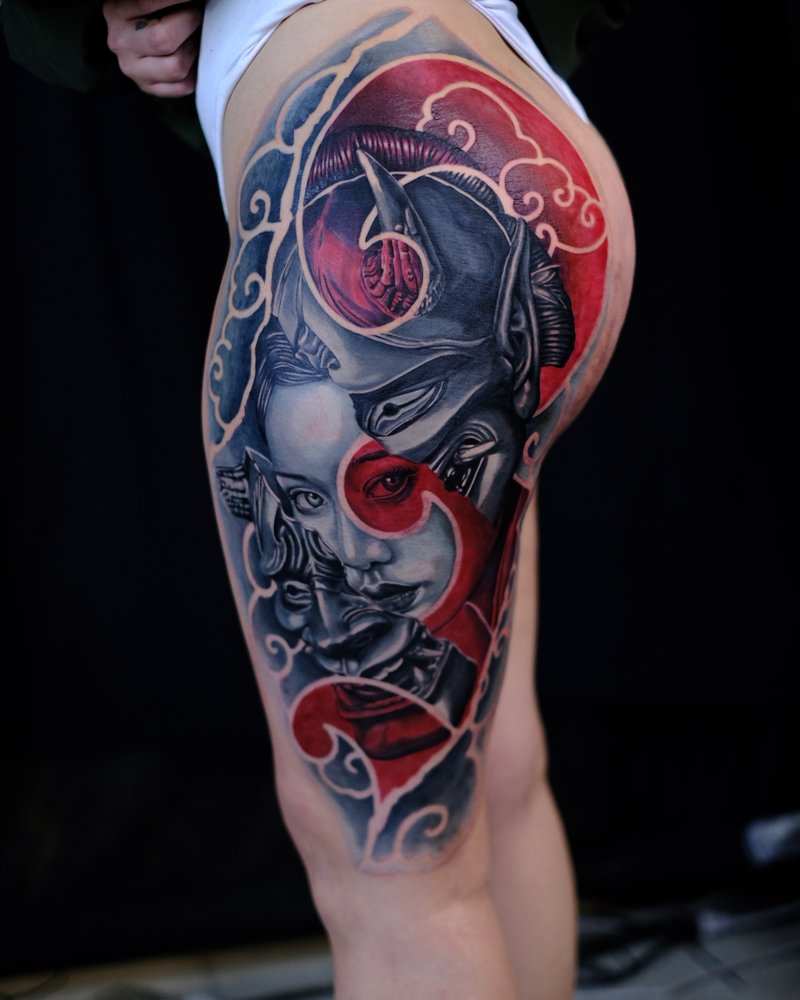 Tatuaje neo-tradicional en rojo y negro de un dragon en el muslo