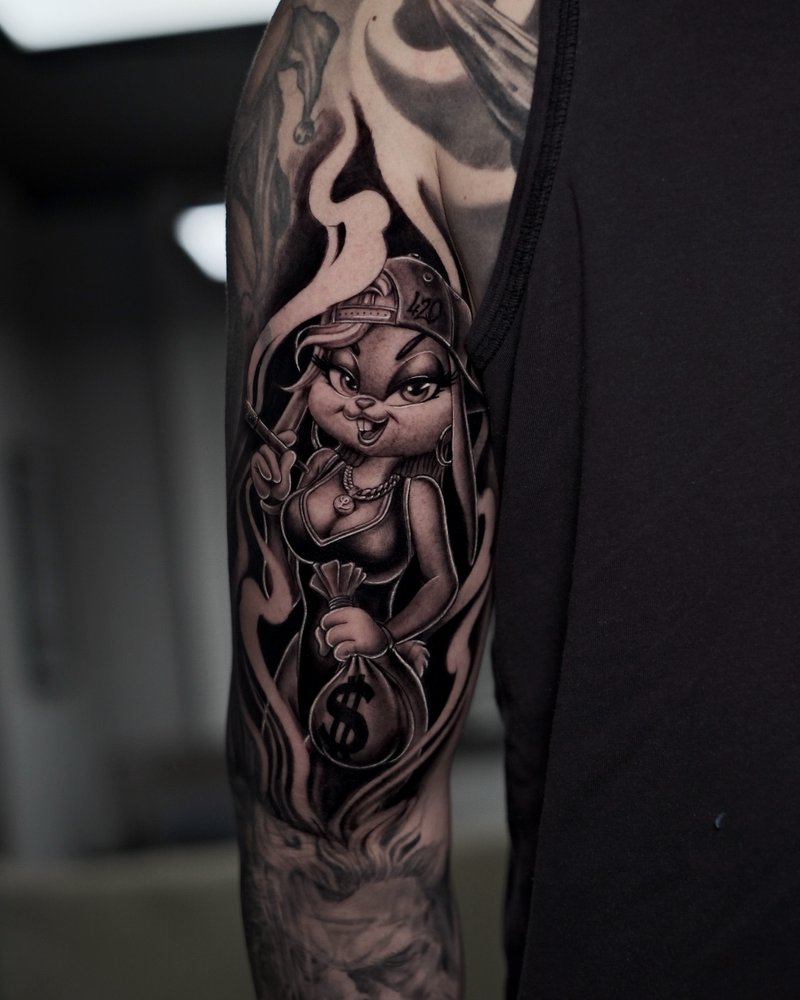 Tatuaje de un personaje de dibujos con una metralleta y un saco de dinero, en el brazo