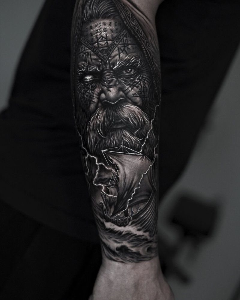 Tatuaje realista en negro y gris de un rostro de anciano con capucha, en el antebrazo