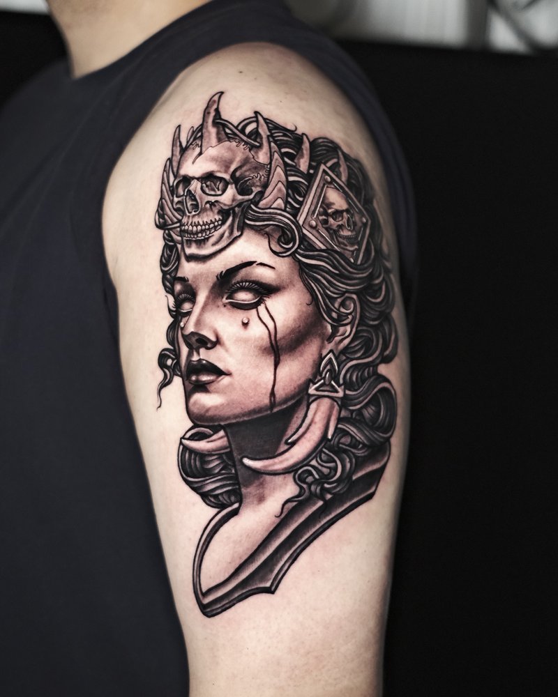 Tatuaje en el brazo de un rostro femenino con una calavera y plumas rosas