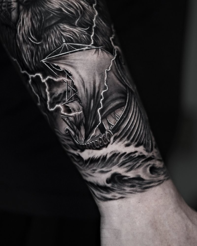 Tatuaje realista en negro y gris: cabeza de lobo con un paisaje y un rayo, en el antebrazo