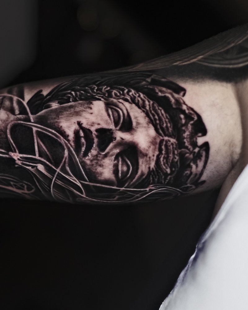 Tatuaje realista en el brazo: retrato femenino en negro y gris integrado en una manga ya tatuada